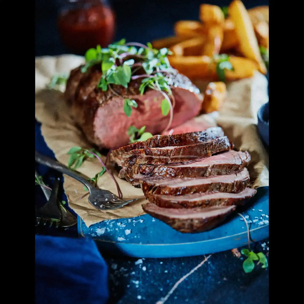 Sliced Australian roast beef garnished with fresh herbs, Peter Augustus premium meat.