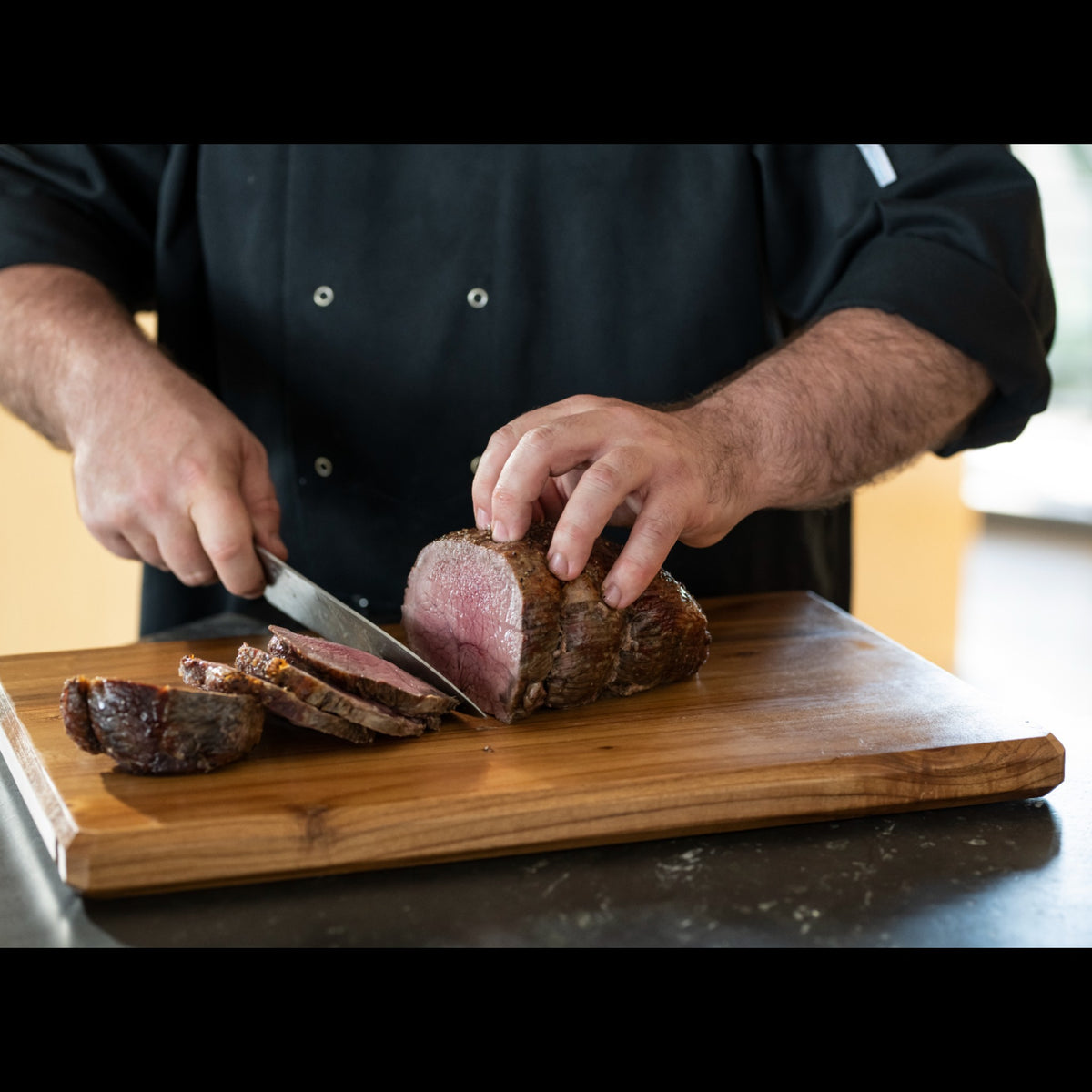 Chef slicing premium roast beef on a wooden cutting board, showcasing juicy Australian beef.
