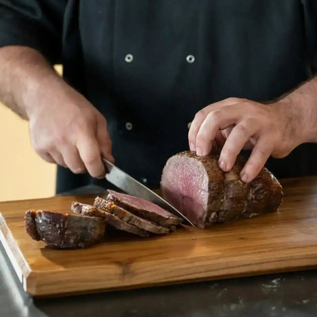 Chef slicing premium roast beef on a wooden cutting board, showcasing juicy Australian beef.