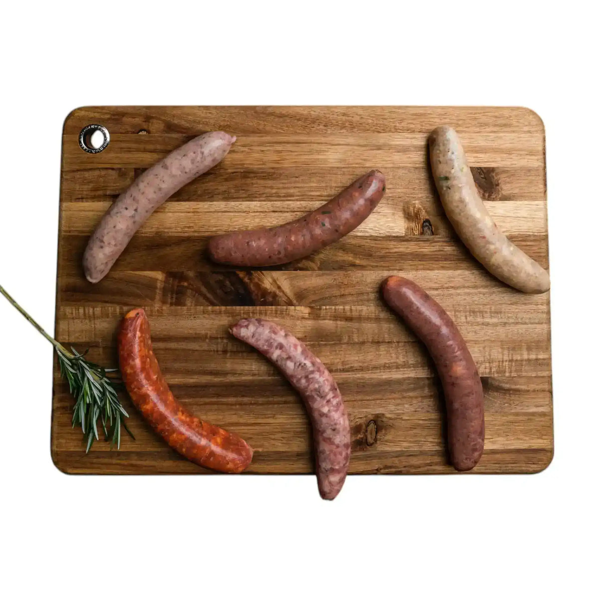 Assorted gourmet sausages on wooden board with rosemary, uncooked, isolated on white