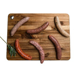 Assorted gourmet sausages from Peter Augustus on wooden board with sprig of rosemary