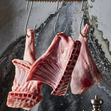 Freshly butchered beef ribs and cuts hanging on hooks, showcasing marbling and quality meat