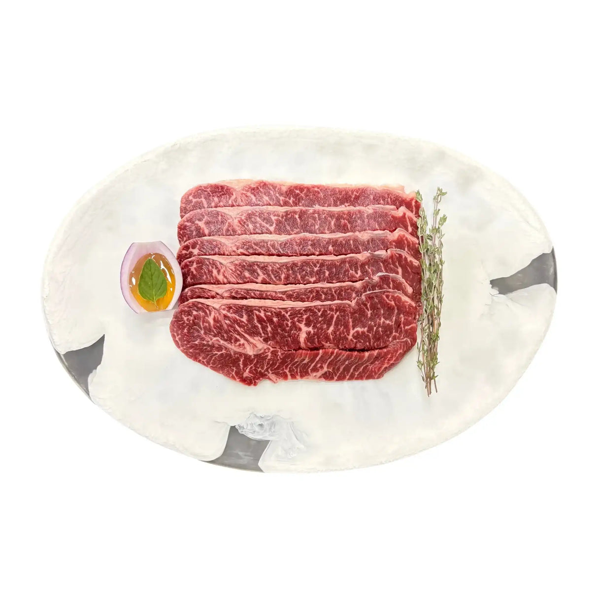 Premium Wagyu beef slices with marbling, served on marble platter with herb garnish and egg yolk