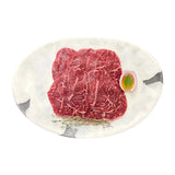 Marbled Wagyu beef slices on white plate with thyme and onion garnish, fresh Australian grass-fed meat