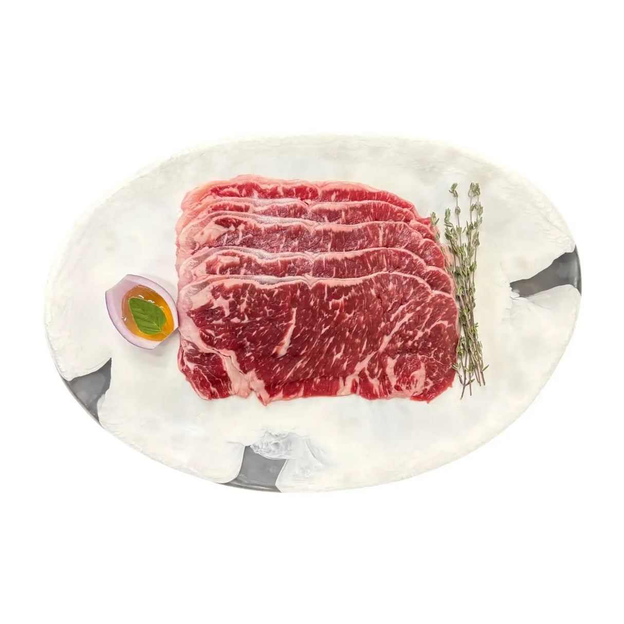Marbled Wagyu beef slices on white plate with thyme and onion, fresh Australian grass-fed beef