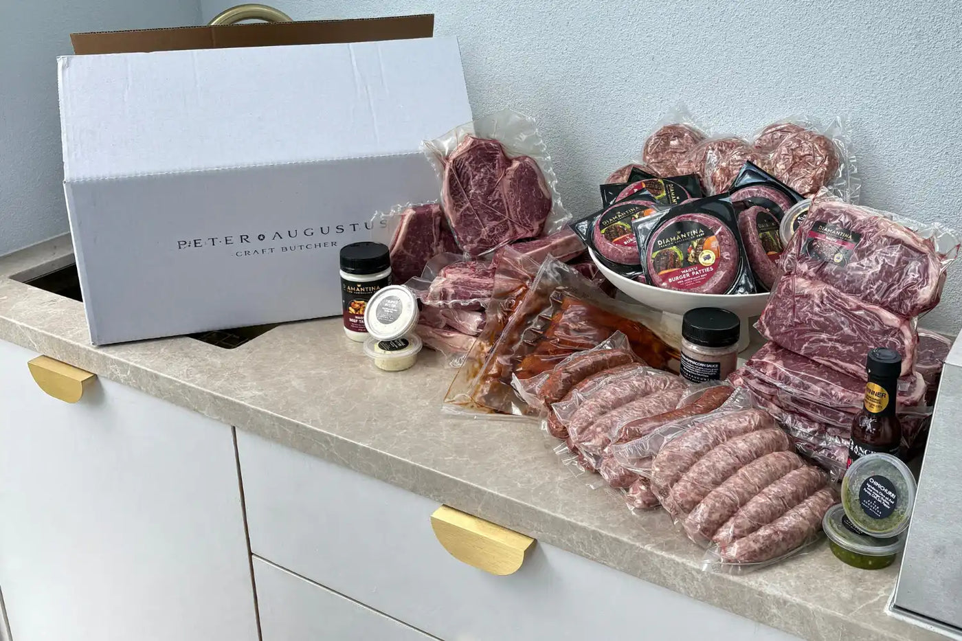 Assorted meats and condiments on a kitchen counter with a branded box.