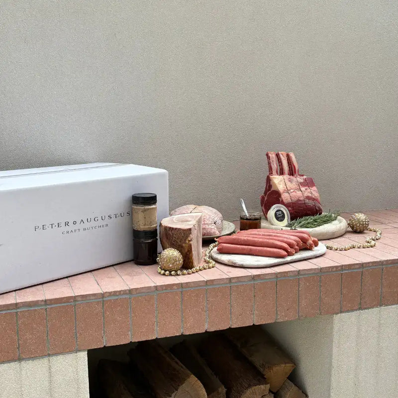 Butcher's counter with meat products and a 'Peter Augustus' branded box.