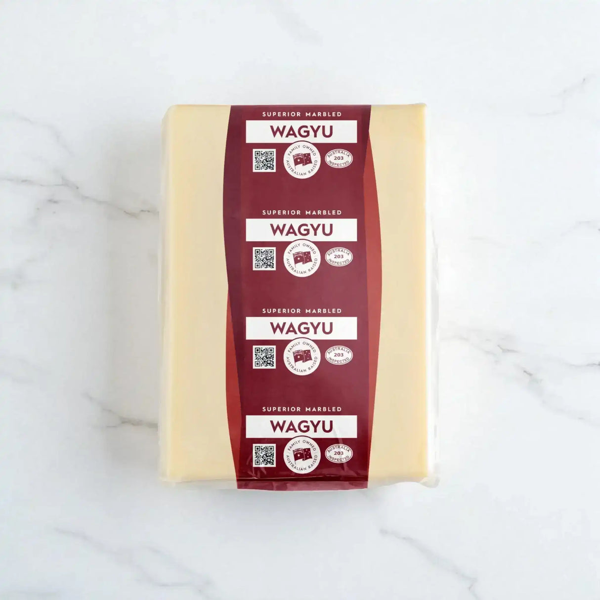 Block of Wagyu beef tallow with maroon superior marbled Wagyu labels on a white marble surface