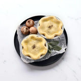 Two small unbaked Wagyu beef pies on a tray with mushrooms and fresh sage leaves