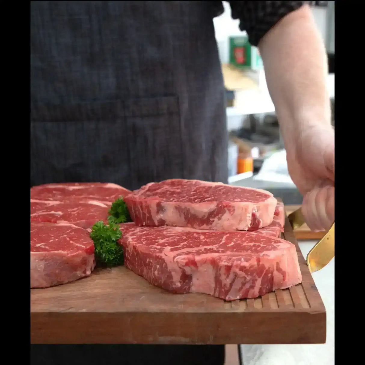 Marbled Wagyu sirloin steaks on a wooden board with parsley garnish