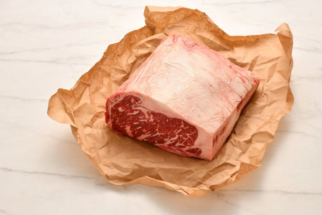 Marbled Wagyu sirloin steak cut resting on brown butcher paper on a white surface