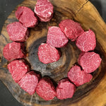 Australian Wagyu beef tenderloin medallions with marbling, displayed on a wooden board