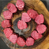 Raw Wagyu beef tenderloin steaks with rich marbling arranged on a rustic wooden board.