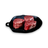 Three marbled beef steaks in a black cast iron skillet, fresh grass-fed beef ready to cook