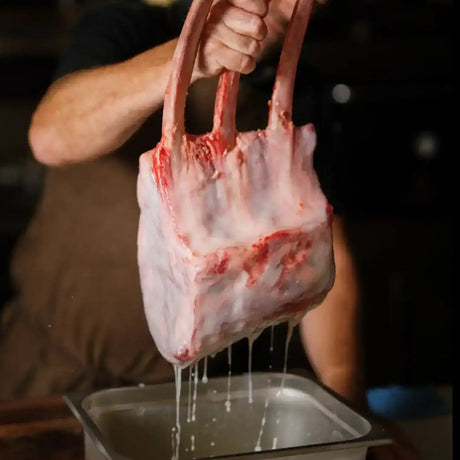 Butcher holding premium Australian beef Tomahawk rib rack above tray, Peter Augustus Craft Butcher